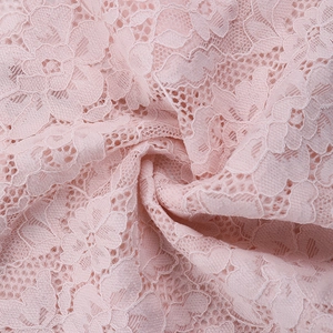 Close-up of pink lace fabric showing intricate floral patterns and sheer texture detail