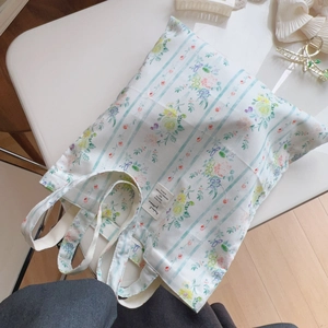 Dettaglio della borsa tote floreale con strisce blu e motivi botanici stampati