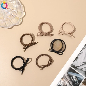 Close-up of 6 elastic hair ties with braided textures and gold metal accents in neutral tones