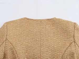 Close-up of golden tweed fabric texture with subtle sequins on a stylish jacket back
