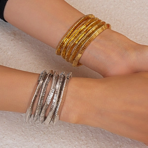 Detail of multi-layer elastic metal bracelets in gold and silver finish on model
