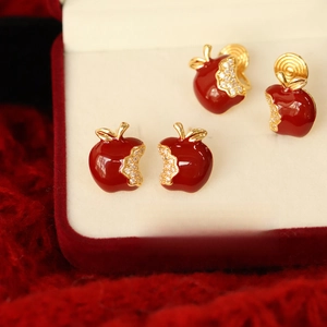Close-up of red enamel apple stud earrings with zircons in a velvet gift box