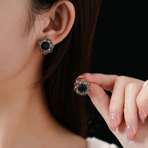 Vintage floral stud earrings with deep blue center stone and crystal halo on ear
