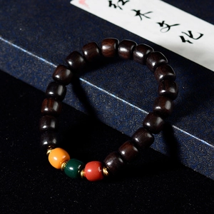 Detail of dark sandalwood prayer beads with colorful accents on a blue vintage box
