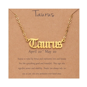 Detail of gold Taurus zodiac necklace with gothic font pendant on character card