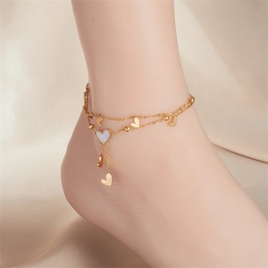 Detail of layered gold ankle chain with heart charms and mother of pearl on silk