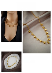 Detail of gold titanium steel necklace featuring polished bead charms on silk background