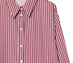 Detail of the sharp collar and white buttons on a red striped poplin shirt