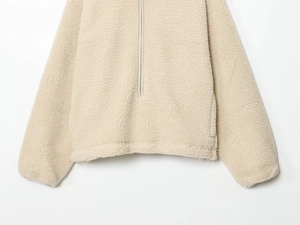 Detailed view of the soft beige fleece fabric and hem of the half-zip teddy sweatshirt