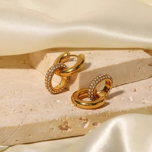 Detail view of gold double-hoop earrings with sparkling pave diamonds on textured stone