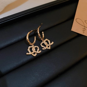 Detailed view of gold twisted heart earrings with cubic zirconia on black leather