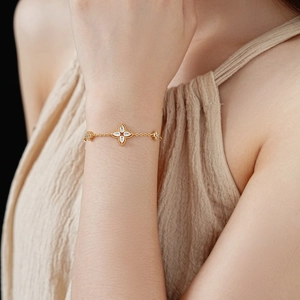 Detail of gold-plated clover bracelet with sparkling zircons on a model's wrist
