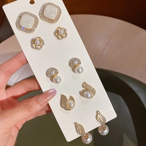 Detail view of 6 pairs of gold-finish earrings with pearls and crystals on a display card