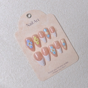 Detail of almond press-on nails with 3D floral carvings and water drop effects