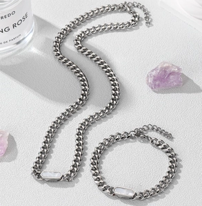 Detail of silver Cuban chain necklace with white shell inlay set against lifestyle props
