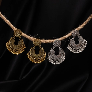 Detailed close-up of bohemian tassel earrings with floral engraving and metallic beads