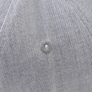 Macro shot of grey twill fabric texture and embroidered eyelets on a flat bill hip hop cap