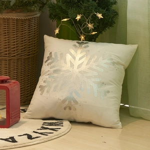 White Christmas pillow cover with silver snowflake print on a cozy festive wooden background