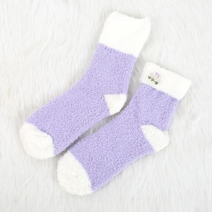 Calze spesse in peluche lavanda e bianco presentate su morbida ecopelliccia bianca