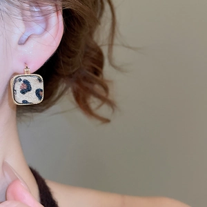 Primo piano di modella con orecchini leopardati quadrati placcati in oro vero 18K