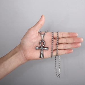 Gros plan d'un pendentif croix punk vintage avec texture serpent et chaîne torsadée