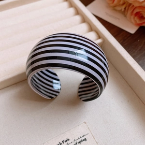 Close-up of wide C-shaped resin bracelet with black and white horizontal stripes