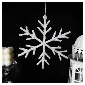 Detailed view of white glitter snowflake ornament hanging against a dark winter background