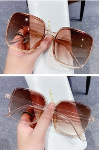 Detail of square oversized tawny sunglasses with gradient lenses and white case