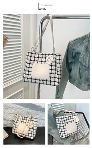 Detail of checkered tweed tote bag featuring white faux leather straps and tiger charm
