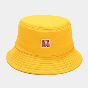 Détail d'un chapeau bob en toile de coton jaune avec écusson blanc lettre Maria