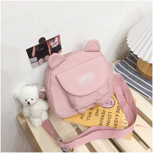 Pink canvas bag with cat ears shown on wooden shelf with cute teddy bear and books