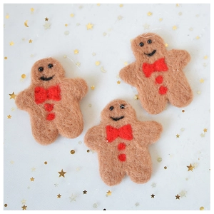 Close-up of three plush gingerbread man ornaments with red bows on star pattern background