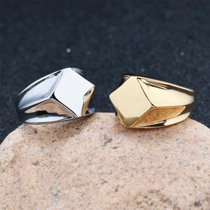 Vista macro di anelli geometrici in acciaio inossidabile argento e oro su una pietra