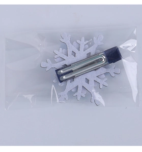 Detailed view of a white snowflake hair clip with a blue ribbon on a metal duckbill clip