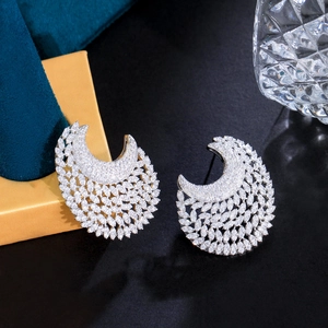 Macro shot of silver crescent earrings featuring pavé-set cubic zirconia on a dark backdrop