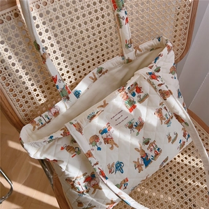 Detail of white quilted tote bag with cute rabbit prints on a vintage wicker chair