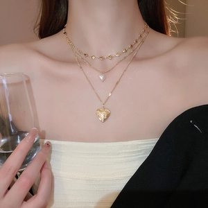 Close-up of triple-layer gold necklace with white and embossed heart-shaped pendants