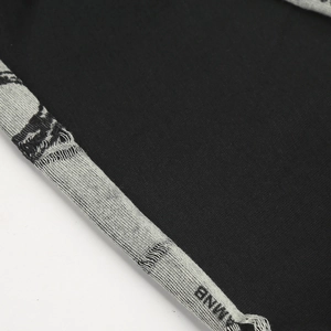 Macro shot of knitted black fabric with AMNB lettering detail and refined texture