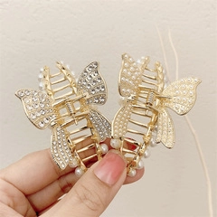 Detail of mini gold butterfly hair claws with crystals and pearls on hand