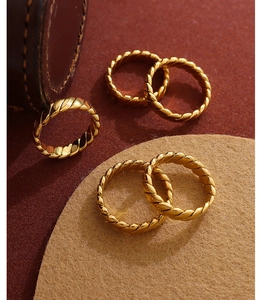 Detailed close-up of five golden braided twist rings with polished 18K gold plated finish