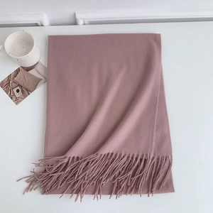 Detailed view of pink cashmere-like scarf showing soft texture and tassel hem