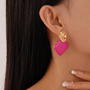 Detailed close-up of golden metallic stud and pink textured faux leather geometric earrings