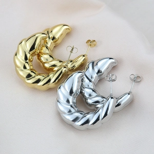 Detailed view of gold and silver textured croissant hoop earrings on soft fabric