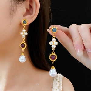 Vintage gold earrings with blue and purple stones plus baroque pearls on a model