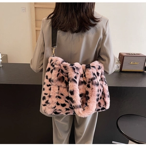Detail of pink leopard plush tote bag with adjustable strap worn on a gray suit