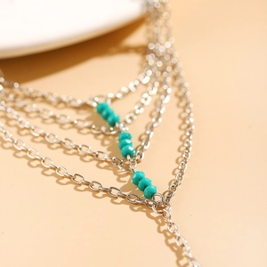 Macro detail of silver layered chain bracelet featuring turquoise beads and link structure