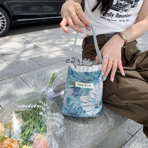 Detail of blue floral fabric mini handbag with white lace trim and Korean text label