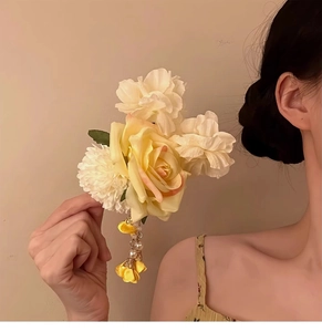 Detail of yellow fabric floral hair clip with white petals, pearls and long tassels
