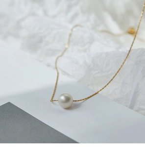 Detail of single white pearl pendant on elegant 18K gold-plated titanium necklace