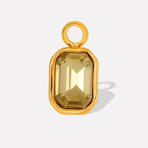 Detailed close-up of a golden geometric pendant with faceted light brown glass gemstone